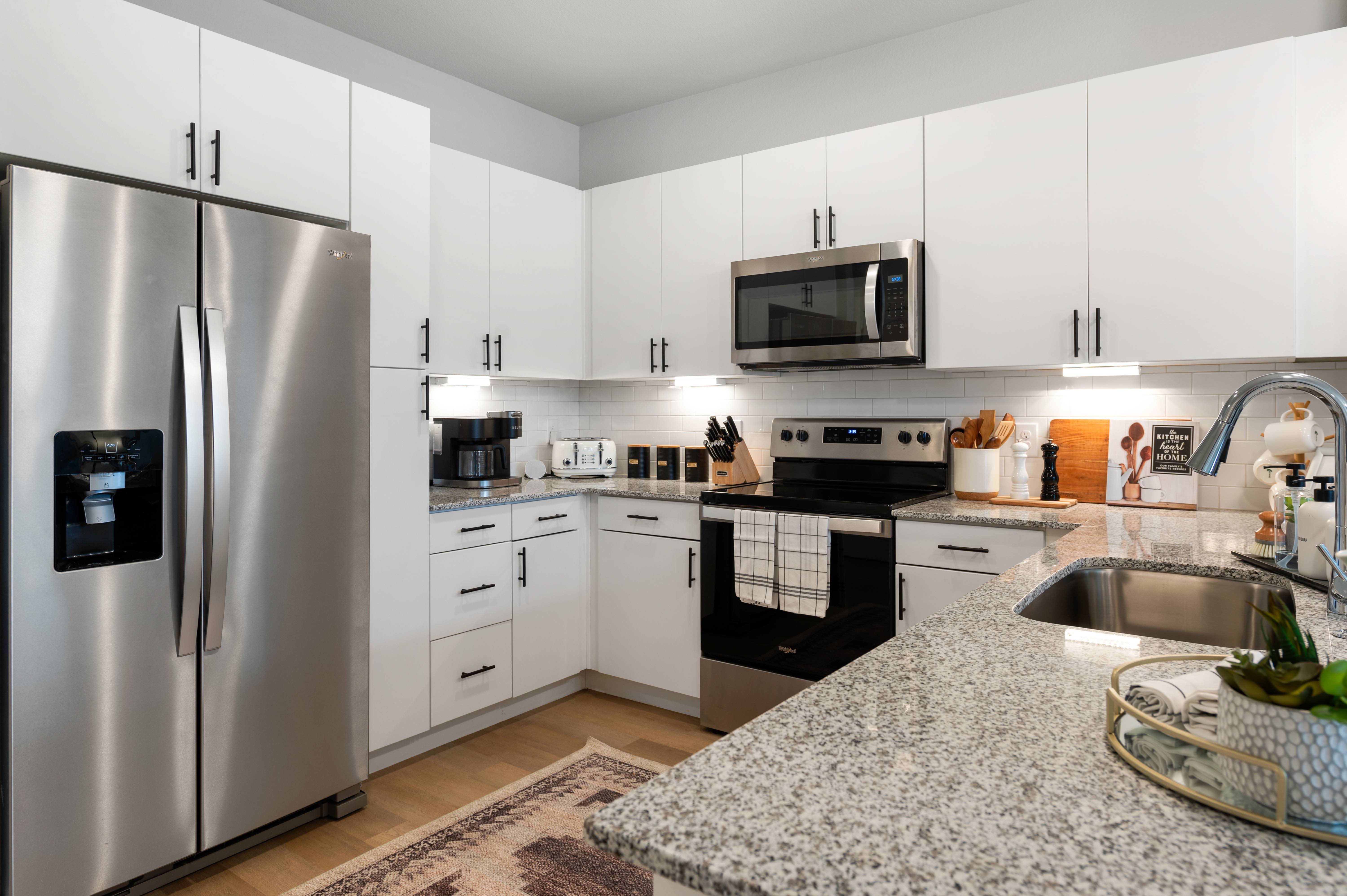 A modern kitchen with a granite countertop and stainless steel appliances.